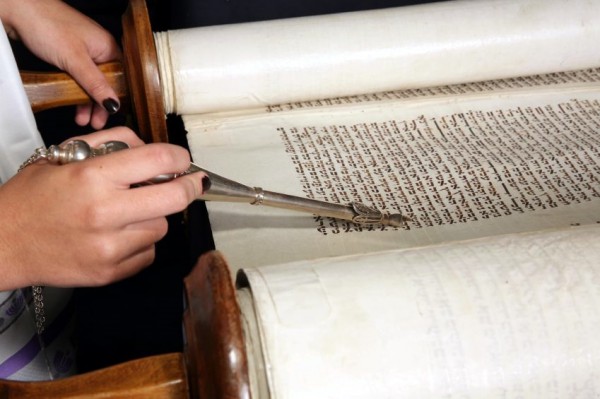 A woman uses a yad (Torah pointer) to follow along in the reading of the Torah portion Torah-yad