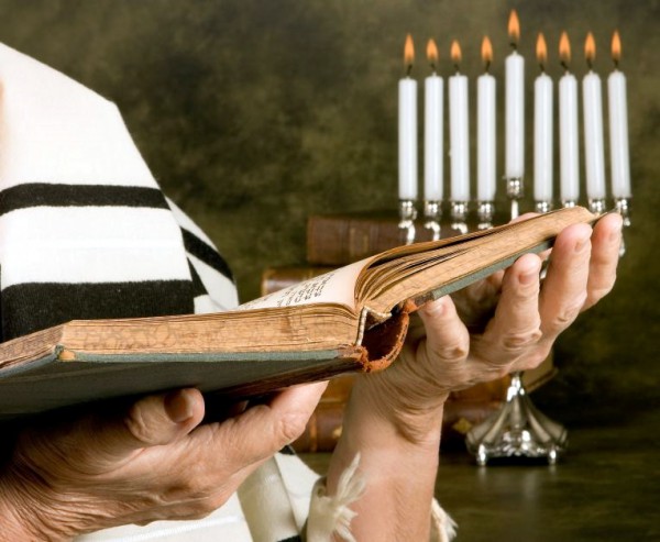 Man reading the Bible beside a chanukiah Bible-menorah-chanukah-chanukiah