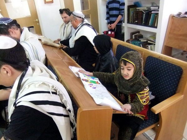 A child wears a Purim costume as he listens to the reading of Esther child-Purim-costume-Esther-synagogue-Ofra-Israel
