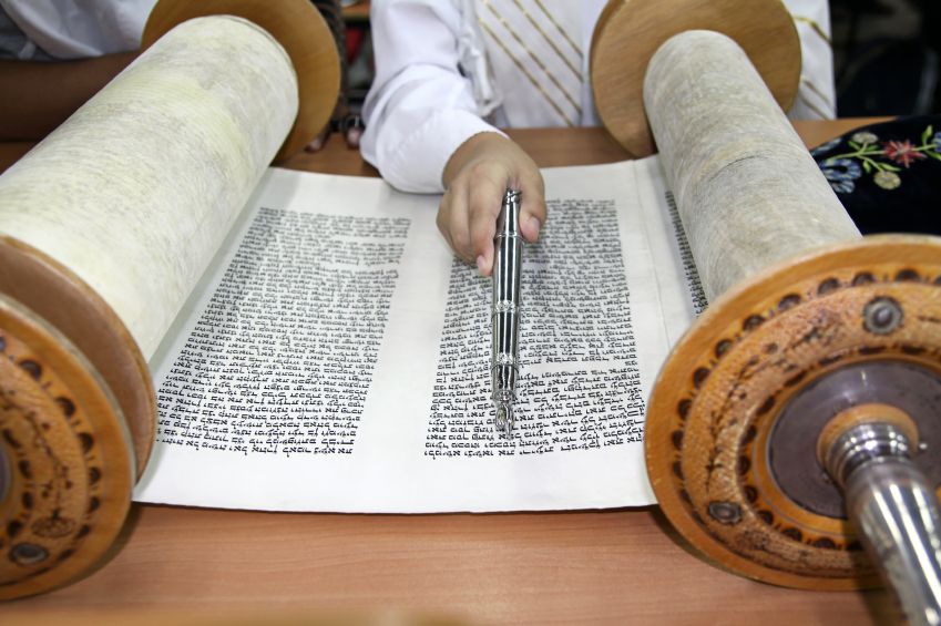 Reading from the opened Sefer Torah (Torah scroll) using a yad (Torah pointer) to follow along in order to protect the precious parchment and handwritten text. The yad also allows others to see the text and ensure that the Torah is read without mistakes.