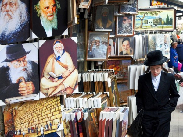 An Orthodox Jewish lad passes by a store in the Mea Shearim neighborhood of Jerusalem that sells paintings of revered rabbis. ultra-Orthodox-frames