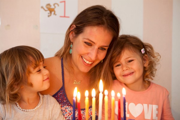 A Jewish mother enjoys the Chanukah lights with her daughters. Chanukah-hanukkah-hanukiah-menorah-lights