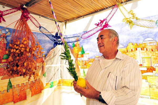A Jewish man prays in a sukkah. Shaking-Lulav-Etrog-Sukkot