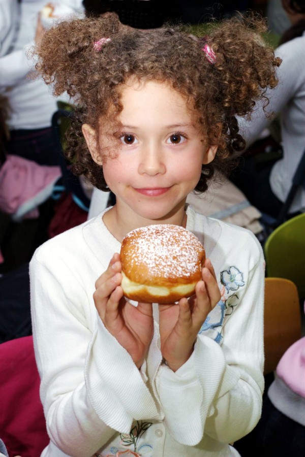 A Jewish girl eats a sufganiyah on Hanukkah. Sufganiyot-donut-chanukkah-hanukkah