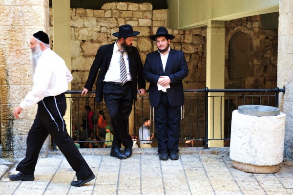 The tzitzit of the tallit katans of two Jewish men are worn outside, while the third man has tucked in his tzitzit. The tzitzit of the tallit katans of two Jewish men are worn outside, while the third man has tucked in his tzitzit.