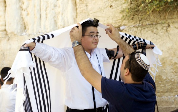 A Jewish father helps his son adjust his tallit gadol during the boy's bar mitzvah at the Western (Wailing) Wall. A Jewish father helps his son adjust his tallit gadol during the boy's bar mitzvah at the Western (Wailing) Wall.