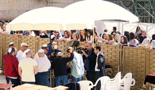 Women observe the Bar Mitzvah of a male relative from behind the fence during a Bar Mitzvah in the men's section at the Western (Wailing) Wall. (Photo by Dan Lundberg) Women observe the Bar Mitzvah of a male relative from behind the fence during a Bar Mitzvah in the men's section at the Western (Wailing) Wall. (Photo by Dan Lundberg)