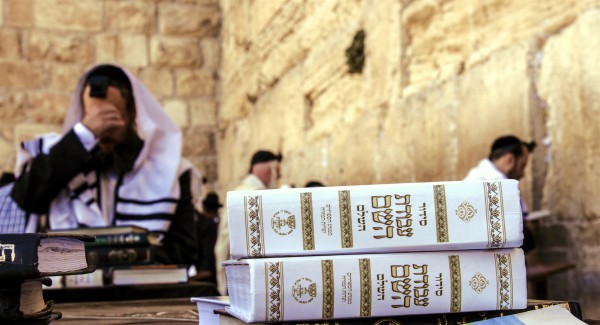 Jewish men pray Shacharit (morning prayers) at Jerusalem's Western (Wailing) Wall. In the foreground are siddurs (Jewish prayer books). Jewish men pray Shacharit (morning prayers) at Jerusalem's Western (Wailing) Wall. In the foreground are siddurs (Jewish prayer books).