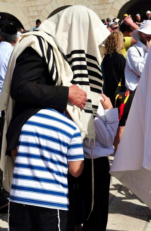 A father pulls his sons under his tallit (prayer shawl) during the Priestly Blessing at the Western Wall in Jerusalem. (Photo by Lilach Daniel) A father pulls his sons under his tallit (prayer shawl) during the Priestly Blessing at the Western Wall in Jerusalem. (Photo by Lilach Daniel)