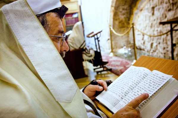 A Jewish man wears a tallit (prayer shawl) and tefillin (phylacteries) as he prays using a siddur (Jewish prayer book) at the Western (Wailing) Wall in Jerusalem. A Jewish man wears a tallit (prayer shawl) and tefillin (phylacteries) as he prays using a siddur (Jewish prayer book) at the Western (Wailing) Wall in Jerusalem.