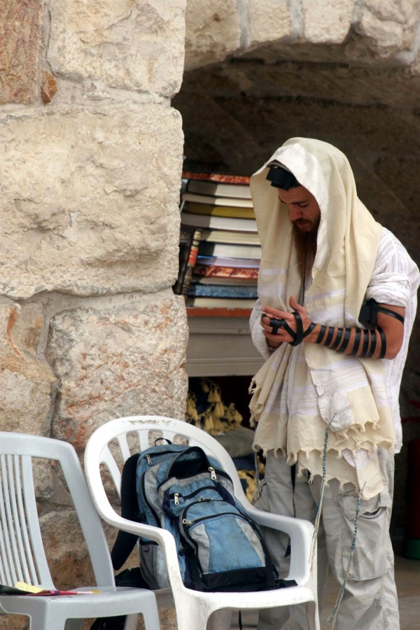 A Jewish man wearing a tallit (prayer shawl) and tefillin (phylacteries) prays at the Western Wall in Jerusalem. A Jewish man wearing a tallit (prayer shawl) and tefillin (phylacteries) prays at the Western Wall in Jerusalem.