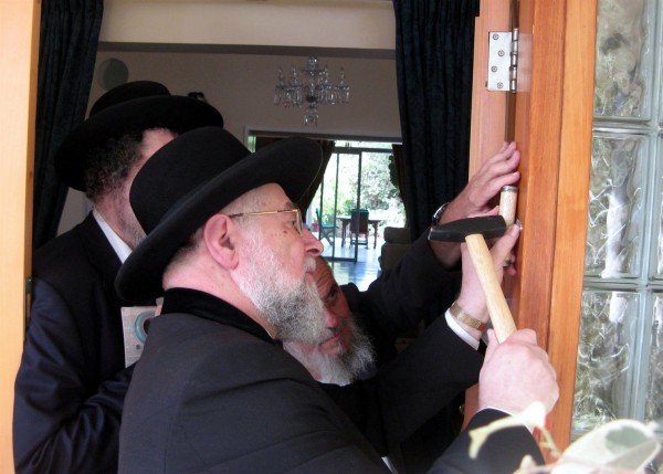 Tel Aviv-Jaffa Chief Rabbi Lau affixes a mezuzah (doorpost) to the front door of the British Ambassador to Israel's Ramat Gan residence. Tel Aviv-Jaffa Chief Rabbi Lau affixes a mezuzah (doorpost) to the front door of the British Ambassador to Israel's Ramat Gan residence in fulfillment of the Biblical injunction to inscribe the words of the Shema "on the doorposts of your house (Deuteronomy 6:9)." The parchment, which is protected in a decorative case, is inscribed with Deuteronomy 6:4–9 and 11:13–21.