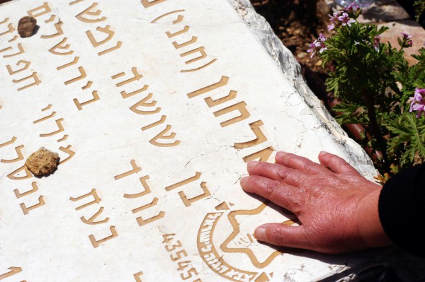 A-relative-of-a-fallen-soldier-puts-a-hand-on-the-grave-of-the-victim-at-a-ceremony-Yom-Hazikaron-at-the-Memorial-Service-for-Victims-of-Terror-on-Mount-Herzl-in-Jerusalem Palestinian terrorism, Yom HaZikaron